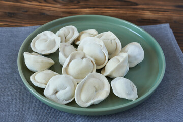 Homemade dumplings on a green plate on a wooden background