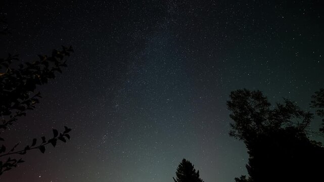 Milky Way with North Star, sky with stars with crossing planes, satellites and perseids meteor showers. A hint of polar light, aurora borealis, is visible. 