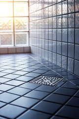 Square shower drain new and clean in tiled floor of modern enclosure in bathroom. New restroom tile floor clean and dry in house.