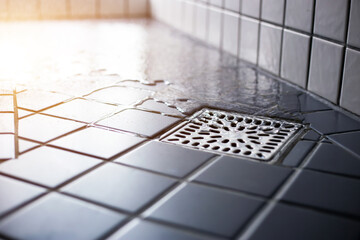 Water flowing to square shower drain hygiene and clean on tiled floor of modern enclosure in bathroom.