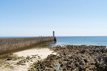 Le phare et le môle du Raoulic à Audierne se détachent sous un ciel estival radieux.