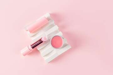 Lip balm, mask, Hygienic lipstick for lip care on an embossed white podium. pink background. Natural cosmetics based on fruit juice