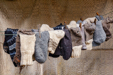 old peasant woolen socks on rope with old wooden hooks with an old carpet in the background