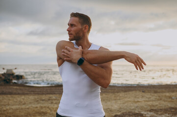 Young strong sporty athletic toned fit sportsman man wearing sports clothes doing stretch hands...