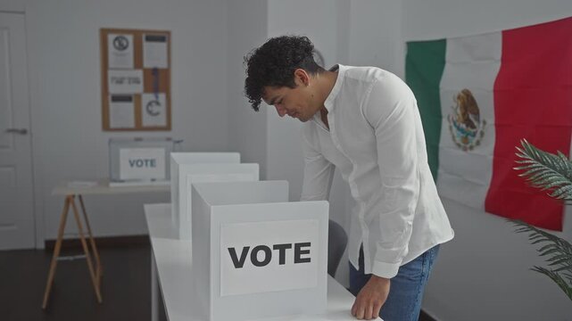 Handsome young man voting in a mexican electoral room with flag in background