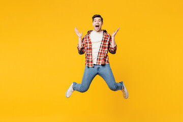 Full body young overjoyed excited happy man he wear red checkered shirt casual clothes jump high spread hands look camera isolated on plain yellow orange background studio portrait. Lifestyle concept