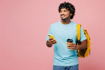 Young Indian boy student wear blue t-shirt casual clothes backpack bag hold cup drink coffee use...