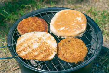 Vegan burgers are grilled on a small camping grill.