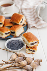 Sweet bun with poppy seed on white table.