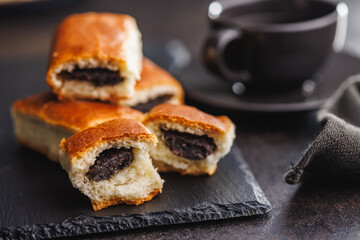 Sweet bun with poppy seed on black table.