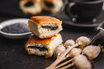 Sweet bun with poppy seed on black table.