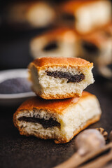 Sweet bun with poppy seed on black table.