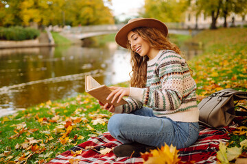 Woman reading a book in the park. Concept of enjoying nature. Autumn mood.