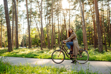 Beautiful happy woman riding bicycle in park. Woman enjoys nature. Active day.