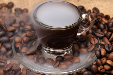 Dark brown Coffee bean macro closeup flow move fall drop pan roll smoking roasting cooking transparent clear glass cup saucer pour liquid on jute fabric background