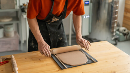 Close-up of potter's hands rolling out clay. 