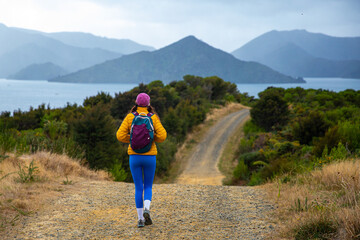 hiker girl enjoys the panorama of picton coastline, new zealand south island; beautiful green hills, small bays and little island; the view from the bobs bay reserve, snout track