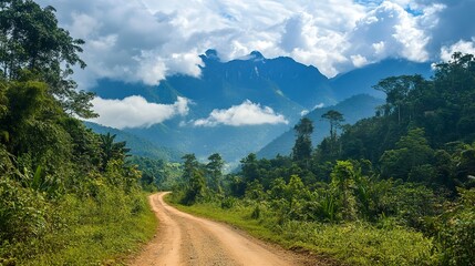 Naklejka premium Jungle landscape and high mountains with clouds and a dirt road in the middle.