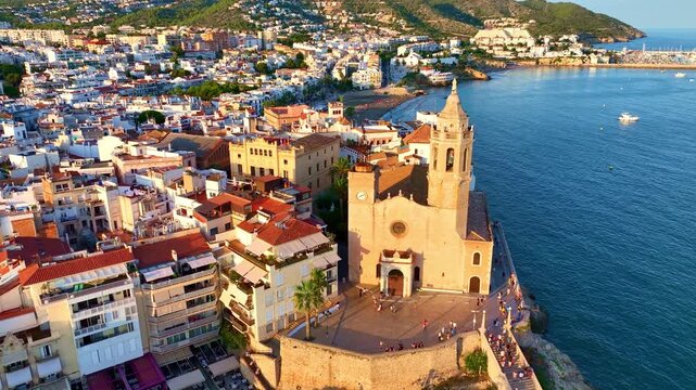 Aerial view of Sitges coastal village and Iglesia de San Bartolome at sunset, holiday in Spain, drone view of Spanish mediterranean village