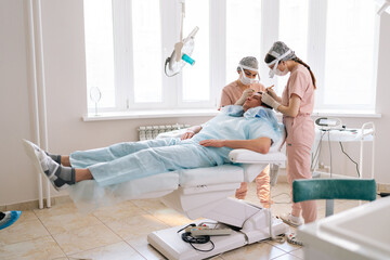 Wide shot of female surgeons carry out hair FUE Sapphire method hair transplant surgery in...
