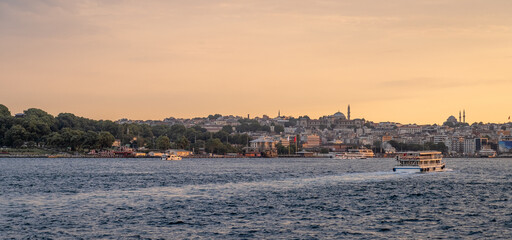 Naklejka premium Stunning sunset view of Istanbul's coastline from the Bosphorus, with the city's