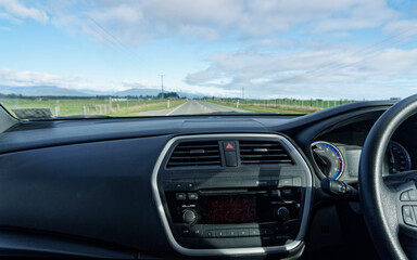 A right hand drive vehicle is being driven along an empty road in New Zealand