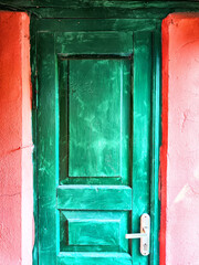 A vibrant green door features a bright light fixture on top of it