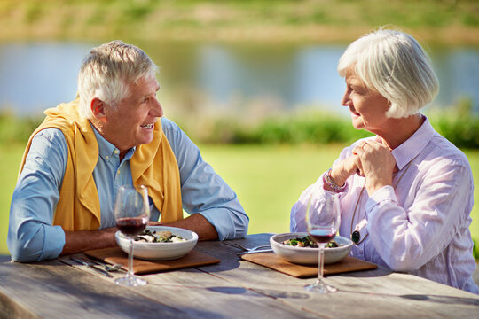 Outdoor, senior couple and meal with wine, love and happiness with healthy food, marriage and joy. Outside, restaurant and mature man with woman, alcohol and nutrition with relationship or retirement