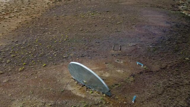 Crash landed flying saucer made from metal crashed into a hill in a semi-arid landscape Camera circling from above