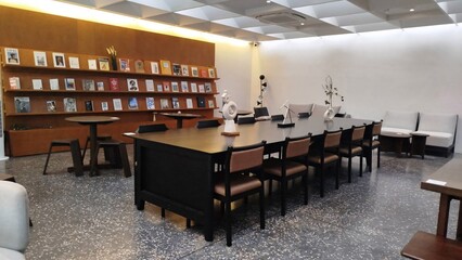 Restaurant room with tables and chairs, featuring books and a light interior design.