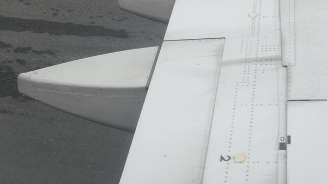 view to aeroplane's wing with flap operation to neutral position after landing arriving to airport while taxi to arrival terminal hall,transportation holiday vacation