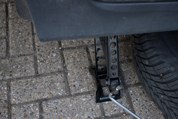 The car is raised on a jack. Jack close-up. Car repair. Maintenance. Wheel replacement. MOT