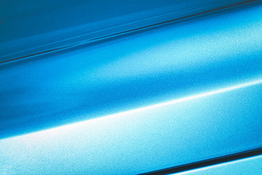 A blue car with a shiny paint job. The car is parked in a parking lot