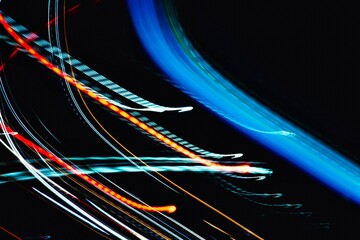 A blurry image of a car with red and blue streaks. Concept of motion and energy, as if the car is speeding down a highway. The streaks of color suggest that the image was taken quickly