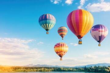 Obraz premium Colorful hot air balloons floating over a lush, green landscape under a clear blue sky, creating a peaceful and picturesque scene.