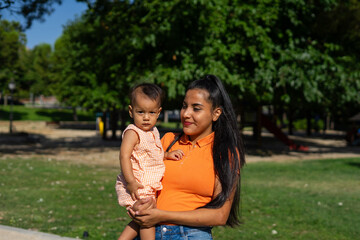 Young Latin mother with her baby daughter in her arms outdoors with copy space