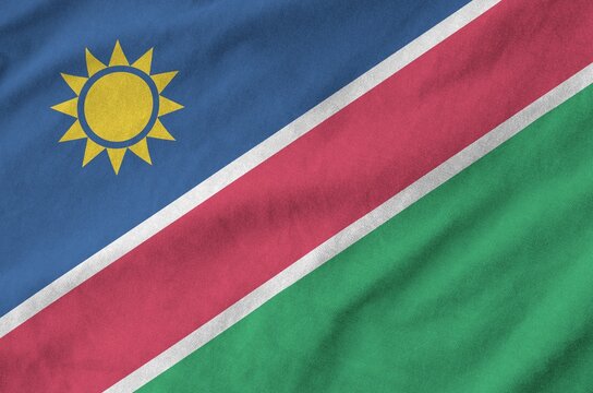 Namibia flag depicted on folded wavy fabric of old cloth close up