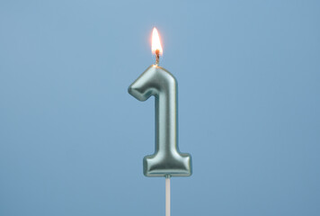 Burning blue birthday candle on blue background, number 1