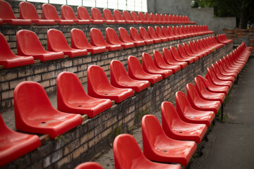 The grandstand at the sports arena. Empty seats in the stadium. Red plastic chairs.