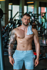 Muscular hunk with posing in gym. Fitness male model near gym equipment. Young muscular man workout. Sport man with strong muscular torso in gym. Sport and motivation. Exercises with weight.
