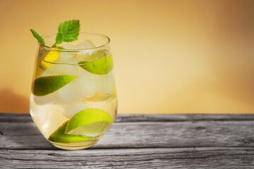 Glass with soda, ice, lemon and lime slices on a bright beige background