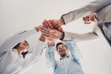 Low angle photo of business people doing team building practice unity gesture in workplace...