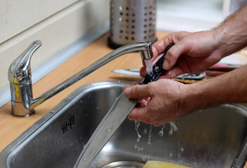 Man washes a knife in kitchen sink 