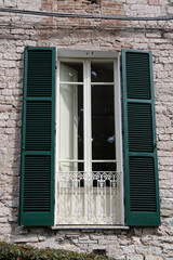 Fototapeta premium View of an old floor-to-ceiling window with a balcony and green shutters