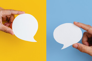 Conceptual image about communication and social media, customer feedback, hand hold blank couple real white speech bubble paper cut on yellow and blue color background
