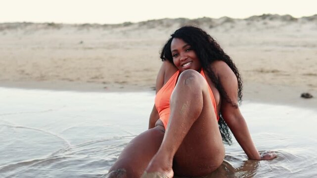 Beautiful African american woman in bikini on tropical beach. Portrait of dark skinned woman smiling at sea. Brunette tanned girl in swimwear enjoying and walking on beach.