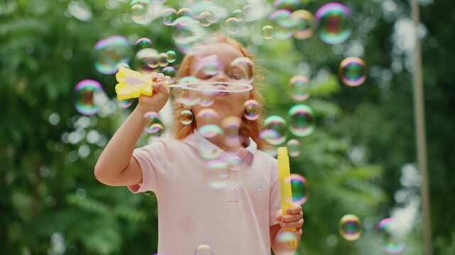 Child blowing bubbles in sunny park surrounded by trees