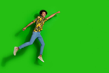 Photo of optimistic positive glad man wear trendy summer print clothes fly air empty space isolated on green color background