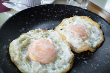 A close-up of fried eggs and fried chicken in a frying pan