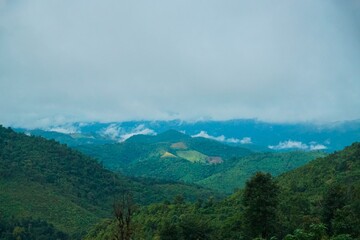 The mountains are covered in lush green trees and the sky is cloudy